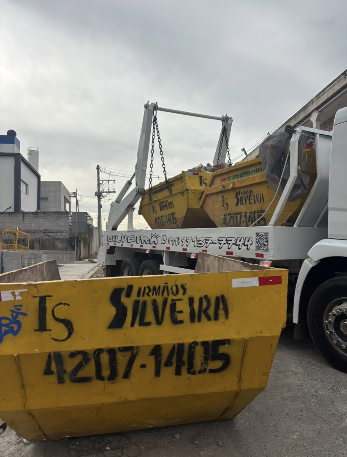 Caçamba amarela da Silveira e caminhão branco de coleta